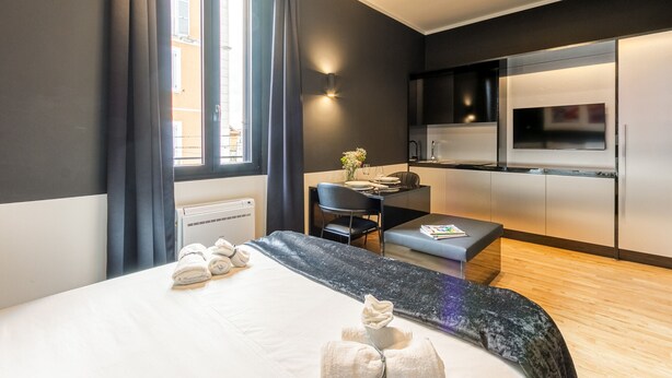 Une chambre d’hôtel moderne équipée d’un lit, d’un bureau et d’une kitchenette.