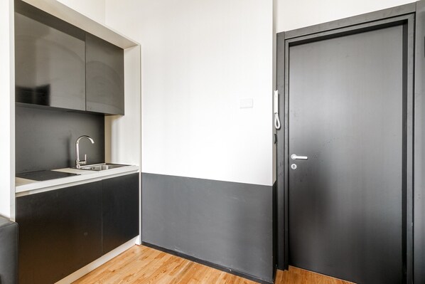 A compact kitchen with a sink, cabinets, and a door.