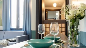 Une table à manger dressée avec des bols turquoise, des verres à vin et un vase contenant des roses blanches.