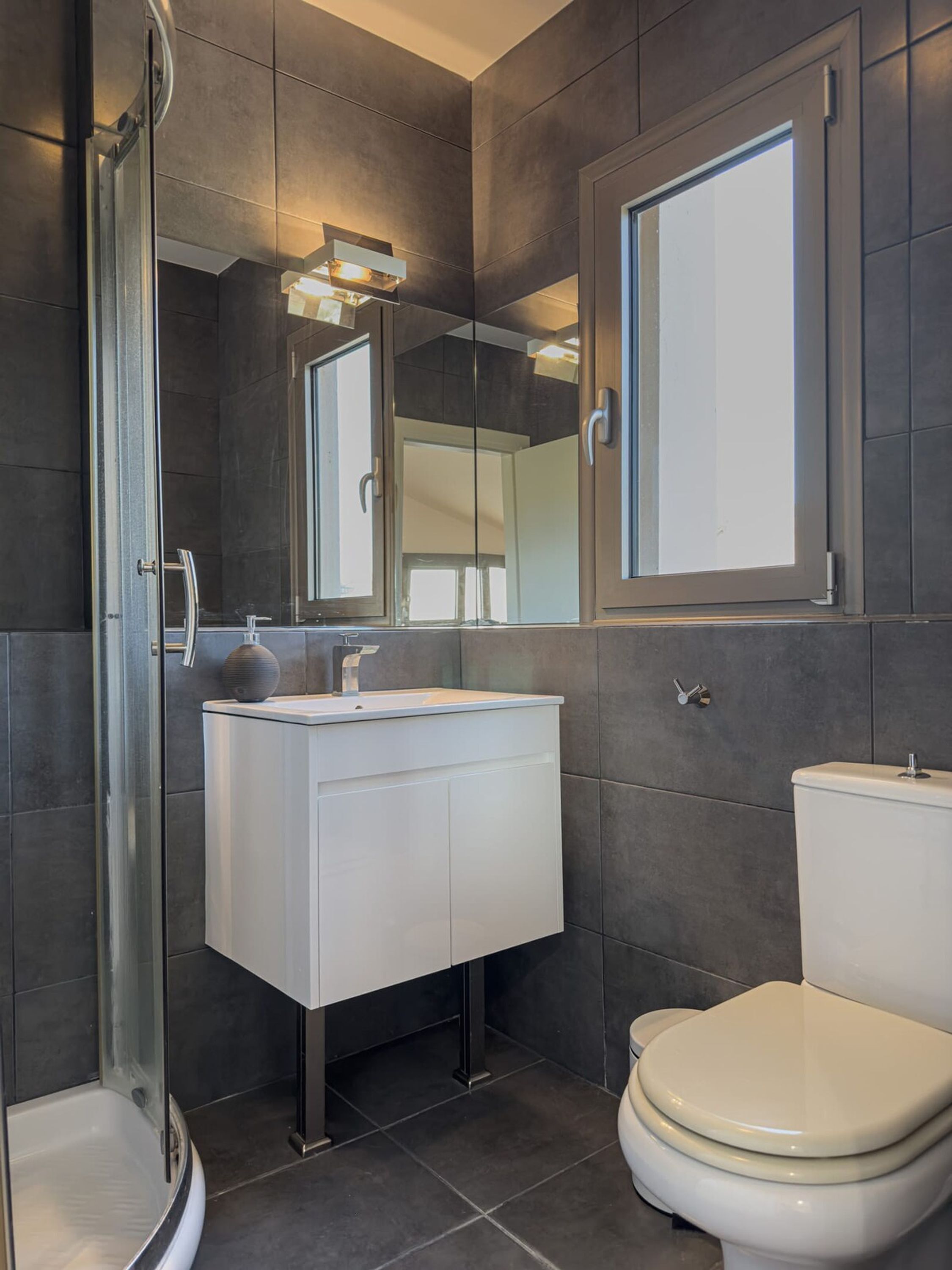 Une salle de bain moderne avec une douche à parois de verre, un lavabo blanc et des toilettes.