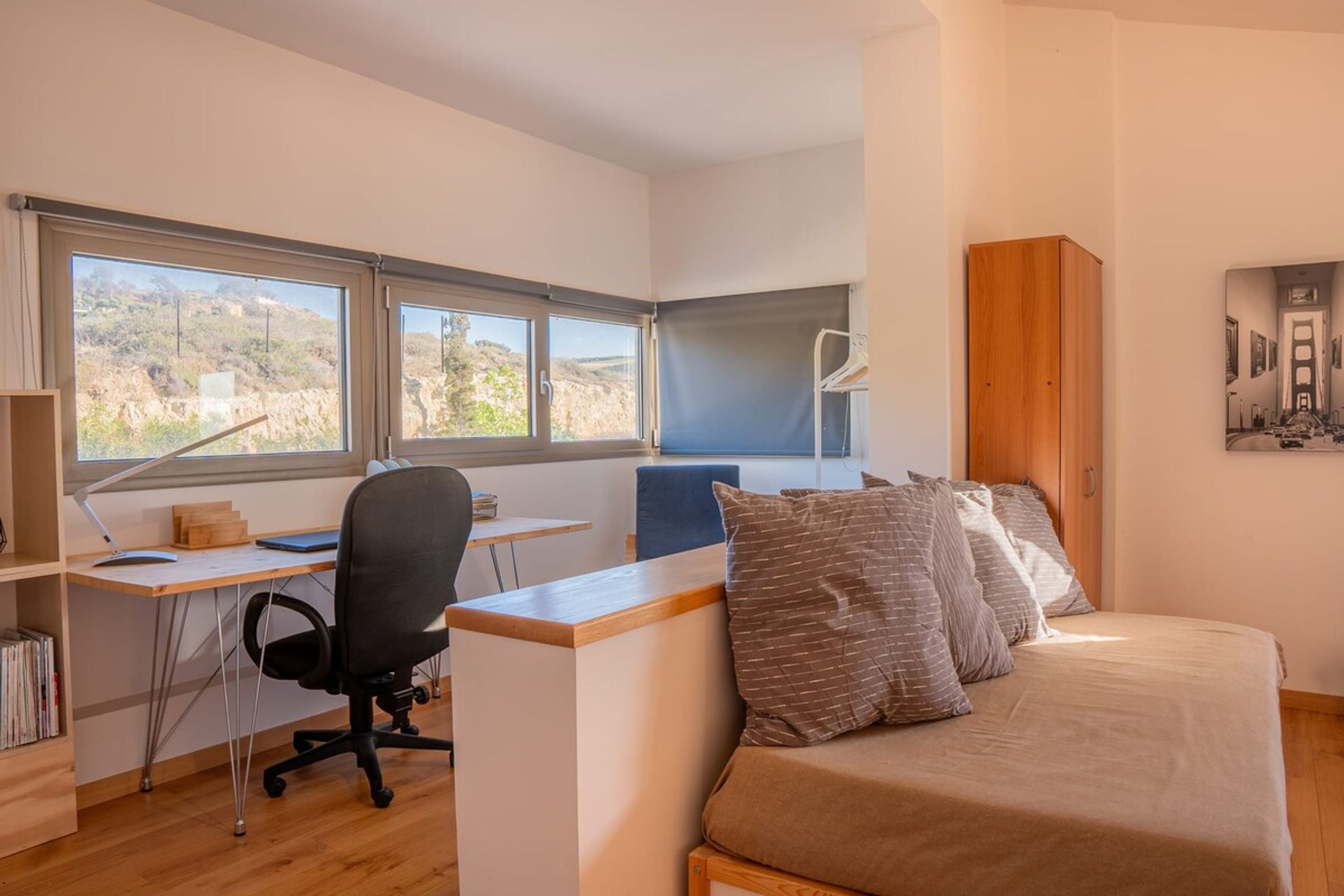 Une chambre à coucher avec un lit, un bureau et deux fenêtres.