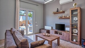 Un soggiorno moderno con divano, tavolino, televisore ed scaffali in legno.