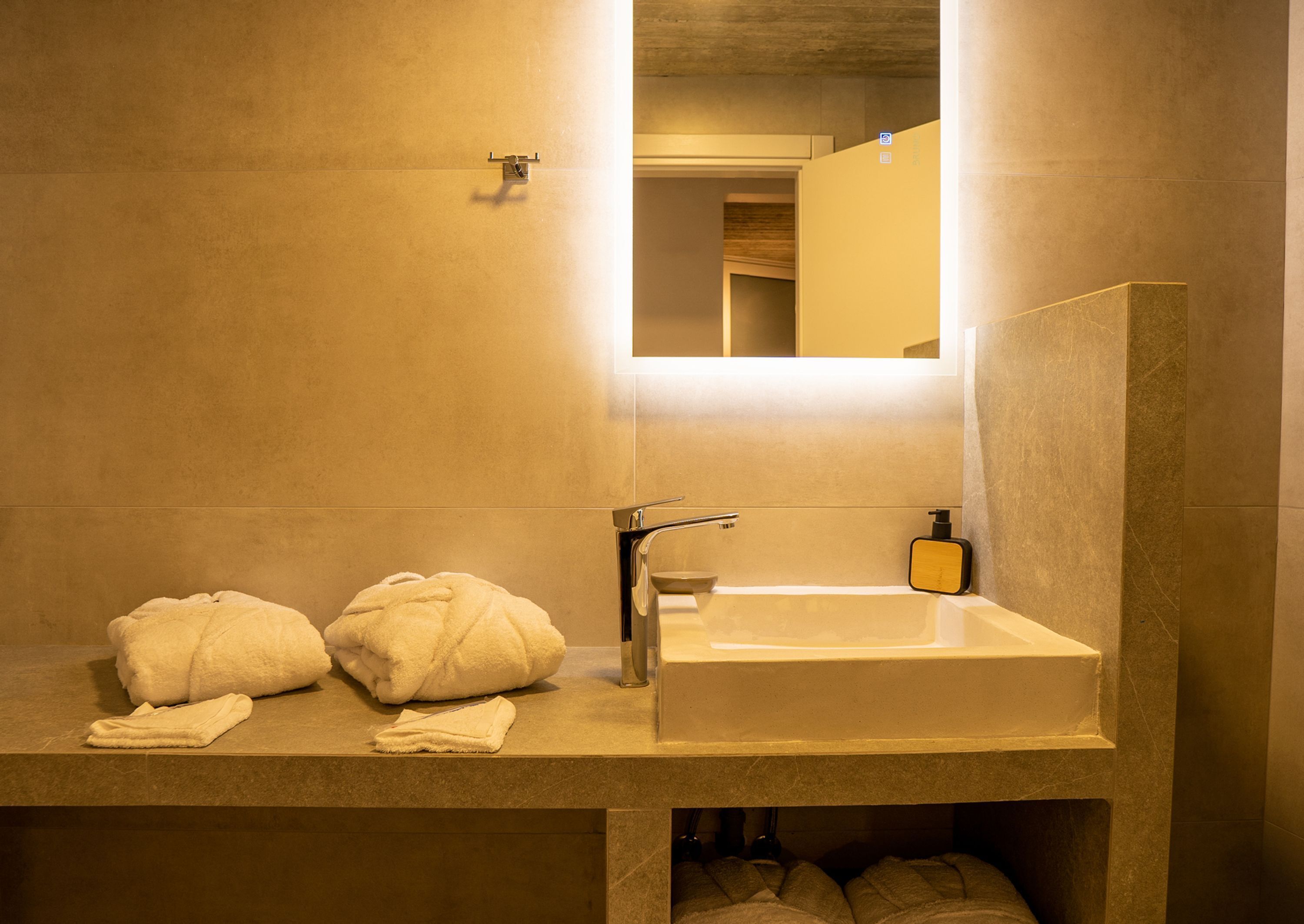 Ein modernes Badezimmer mit einem großen Spiegel, einem Waschbecken und zwei Handtüchern auf der Ablagefläche.