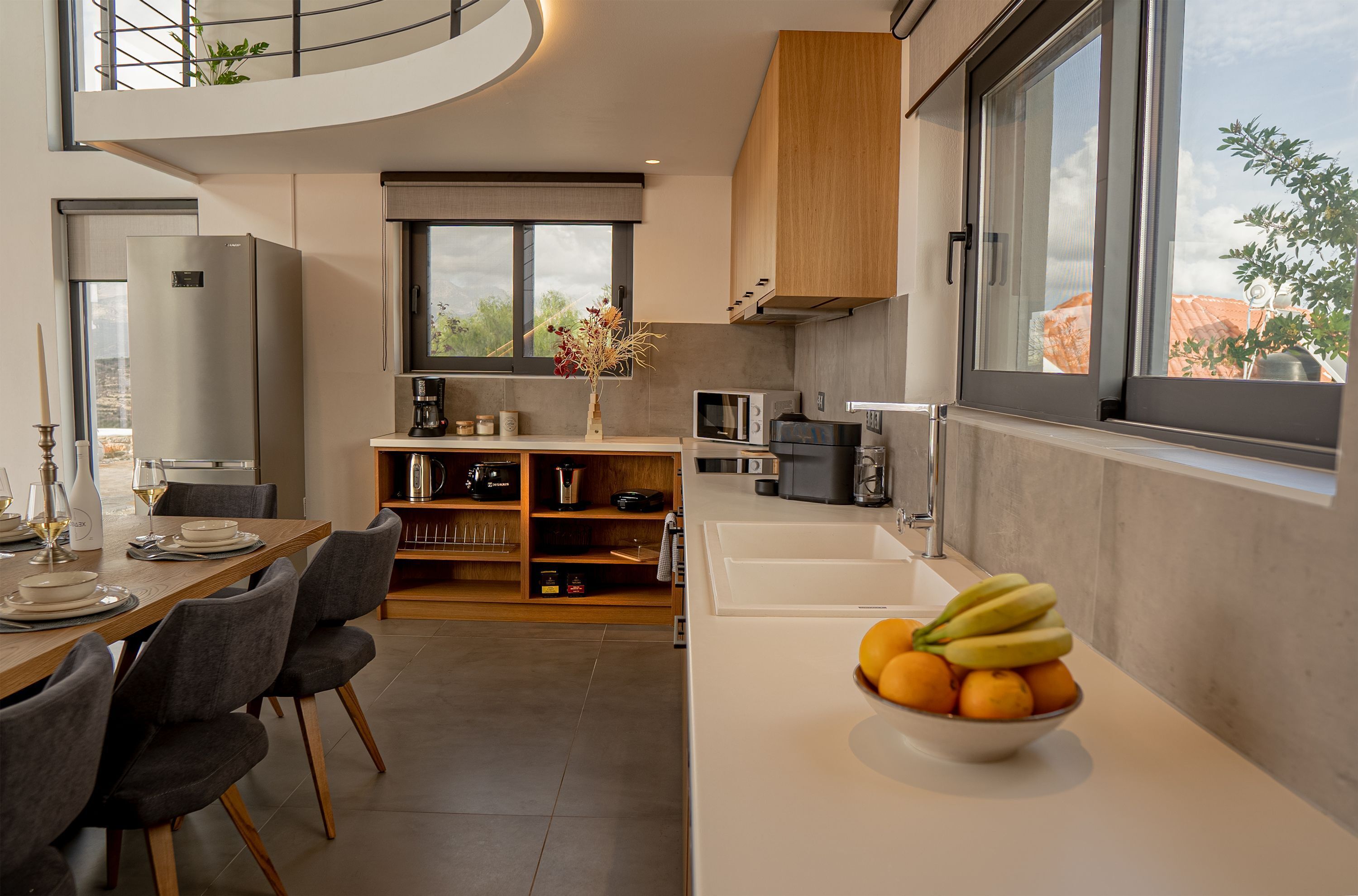 A modern kitchen with a dining area, a built-in oven, and a large window overlooking the city.