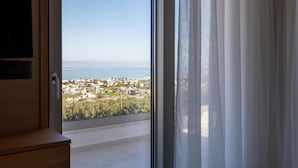 Una habitación con vistas a un pueblo costero a través de un ventanal grande.