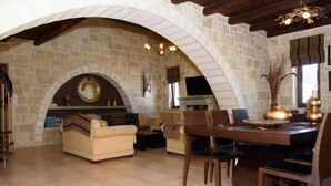 Un vaste espace de vie comprenant une cheminée en pierre, un canapé, une table à manger avec des chaises et un téléviseur.