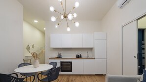 Une cuisine moderne avec des meubles blancs, un îlot central et un coin repas comprenant une table ronde et des chaises.