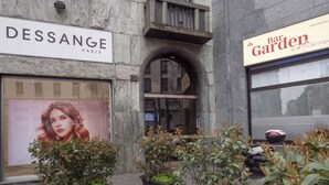 Un bâtiment arborant les enseignes « DESSANGE PARIS » et « Bar Garden di Antonio », caractérisé par une façade en pierre, une entrée en arc de cercle et des plantes en pot disposées au premier plan.
