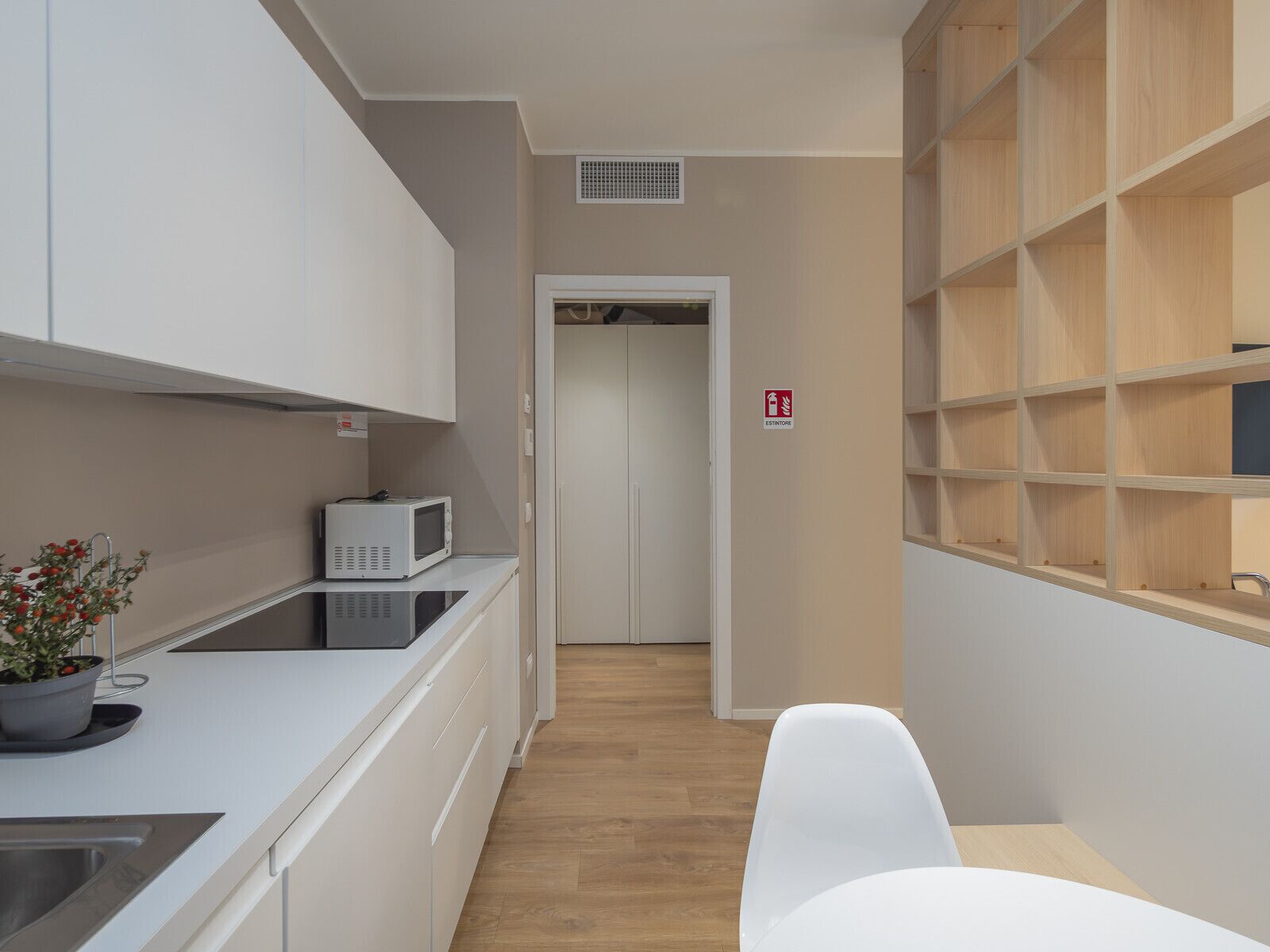 A modern kitchen with white cabinets, a microwave, and a potted plant on the counter.