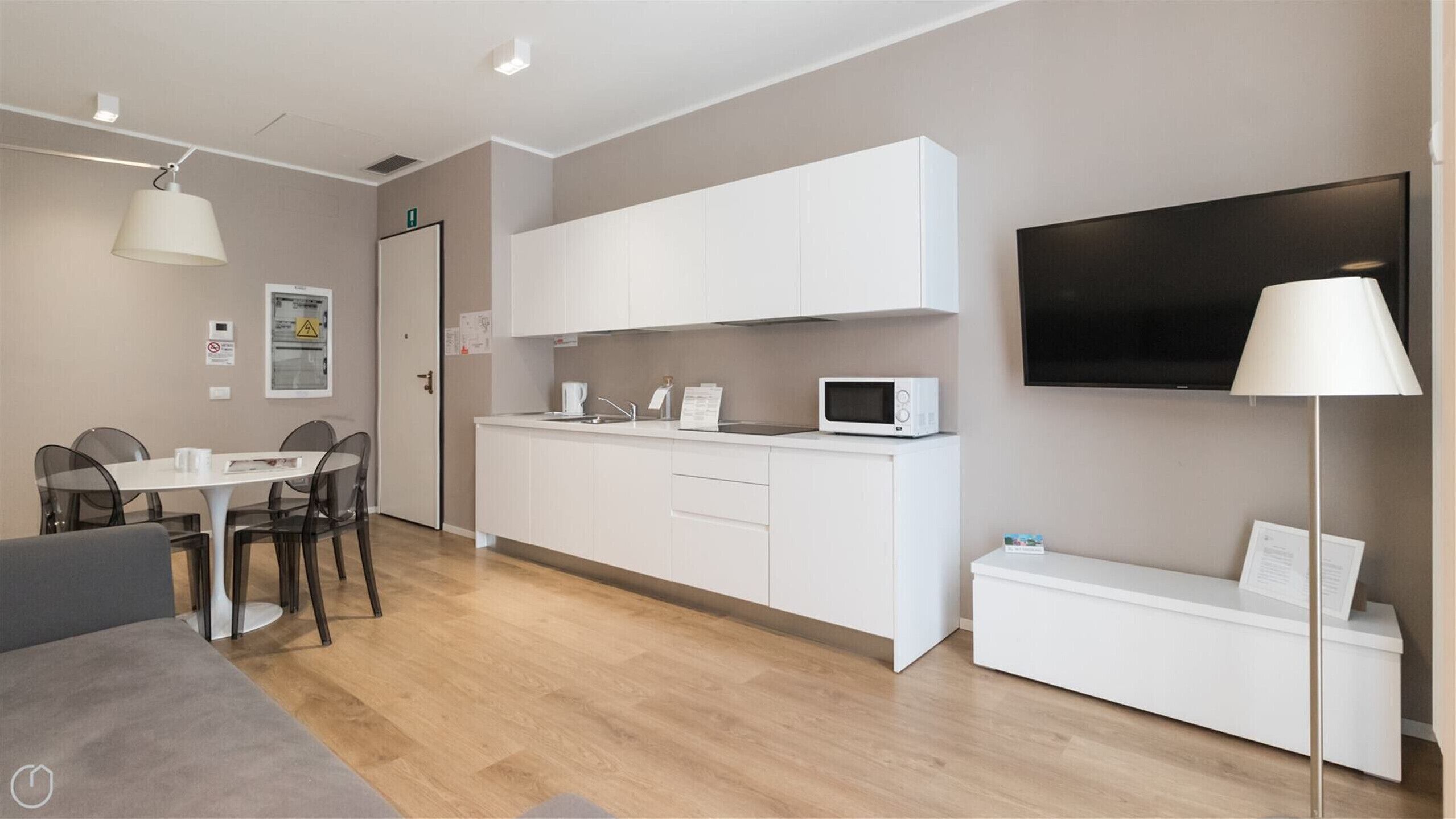 Un espace de vie moderne et compact comprenant une kitchenette, un coin repas et un téléviseur à écran plat.