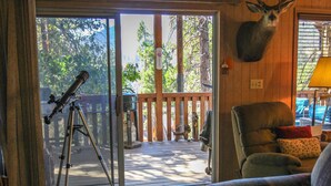 A wooden cabin interior with a telescope, a plush sofa, and a deer head mounted on the wall. - Little Slice of Heaven (Wofford Heights)