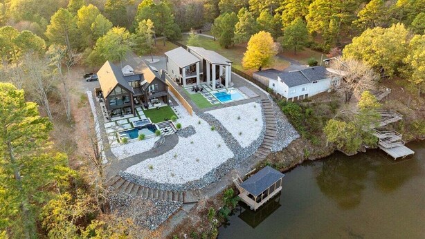 Un vaste domaine comprenant plusieurs bâtiments, une piscine et un quai au bord d’un lac.