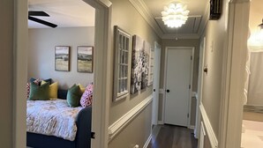 A hallway with a bed, framed pictures, and a door at the end. - Newly renovated home in Quiet Neighborhood. Great for Families (Dunn)