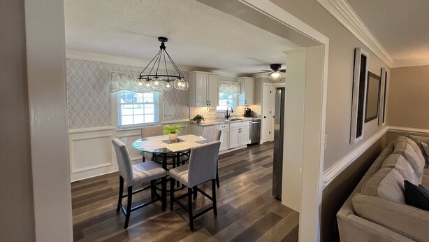 A modern kitchen with a dining area, featuring a round table with chairs, a chandelier, and a built-in oven. - Newly renovated home in Quiet Neighborhood. Great for Families (Dunn)