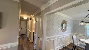 A hallway with a dining area featuring a round mirror and a chandelier. - Newly renovated home in Quiet Neighborhood. Great for Families (Dunn)