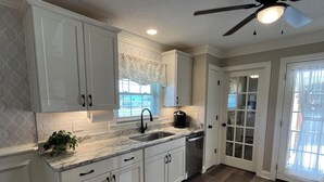 A kitchen with white cabinets, a marble countertop, a black faucet, and a coffee maker. - Newly renovated home in Quiet Neighborhood. Great for Families (Dunn)