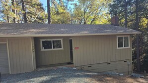 A single-story building with a gravel driveway, a garage, and a small porch area. - Relaxing cabin in the woods. Unplug. Listen to the birds.  Smell the pines. (Pioneer)