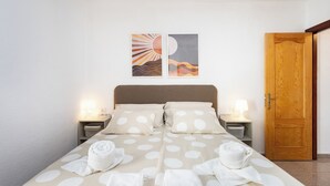A neatly made bed with white polka dot bedding and towels, two bedside lamps, and a wooden door. - Home2Book Vibrant Las Américas Apt, Pool Retreat (Playa de la Américas)