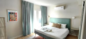 Een hotelkamer met een bed, een nachtkastje, een wandairconditioner en een poster aan de muur.
