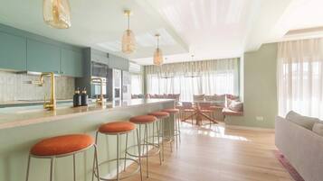 A modern kitchen with bar stools, a dining area with a table and chairs, and a living room with a sofa.