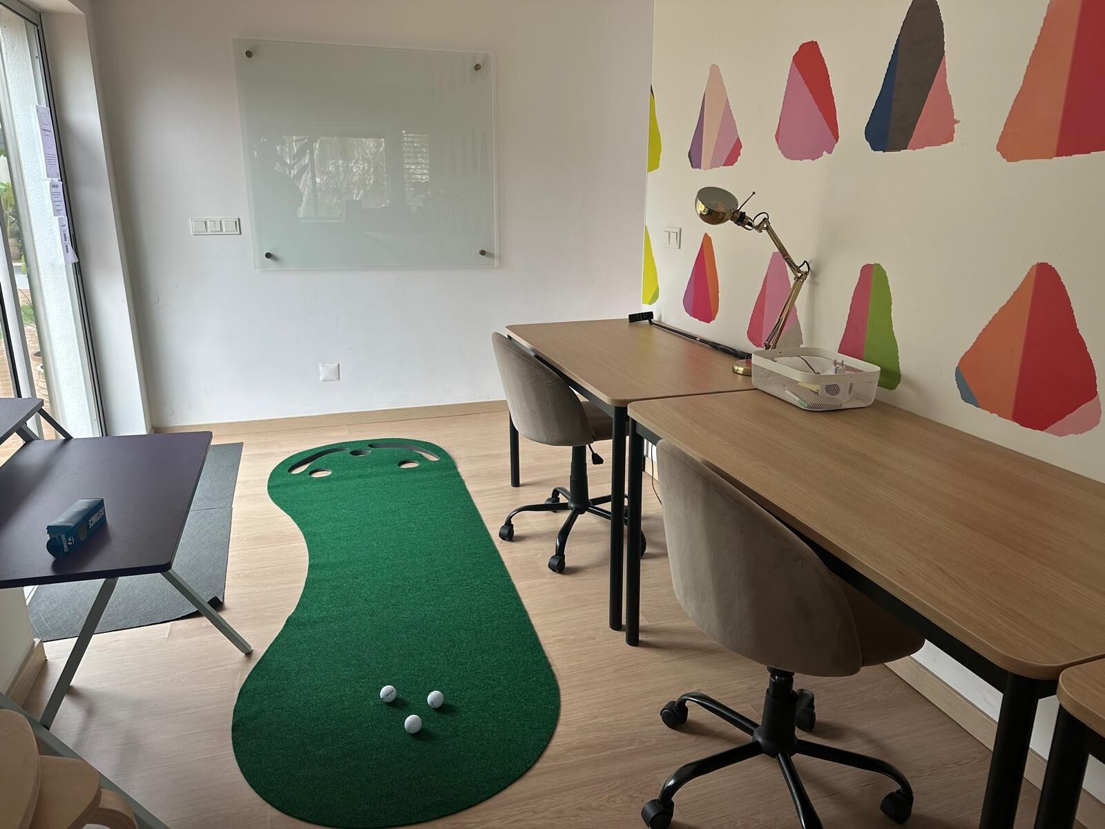 Une pièce avec un tapis vert, un tableau blanc, un bureau et une chaise.