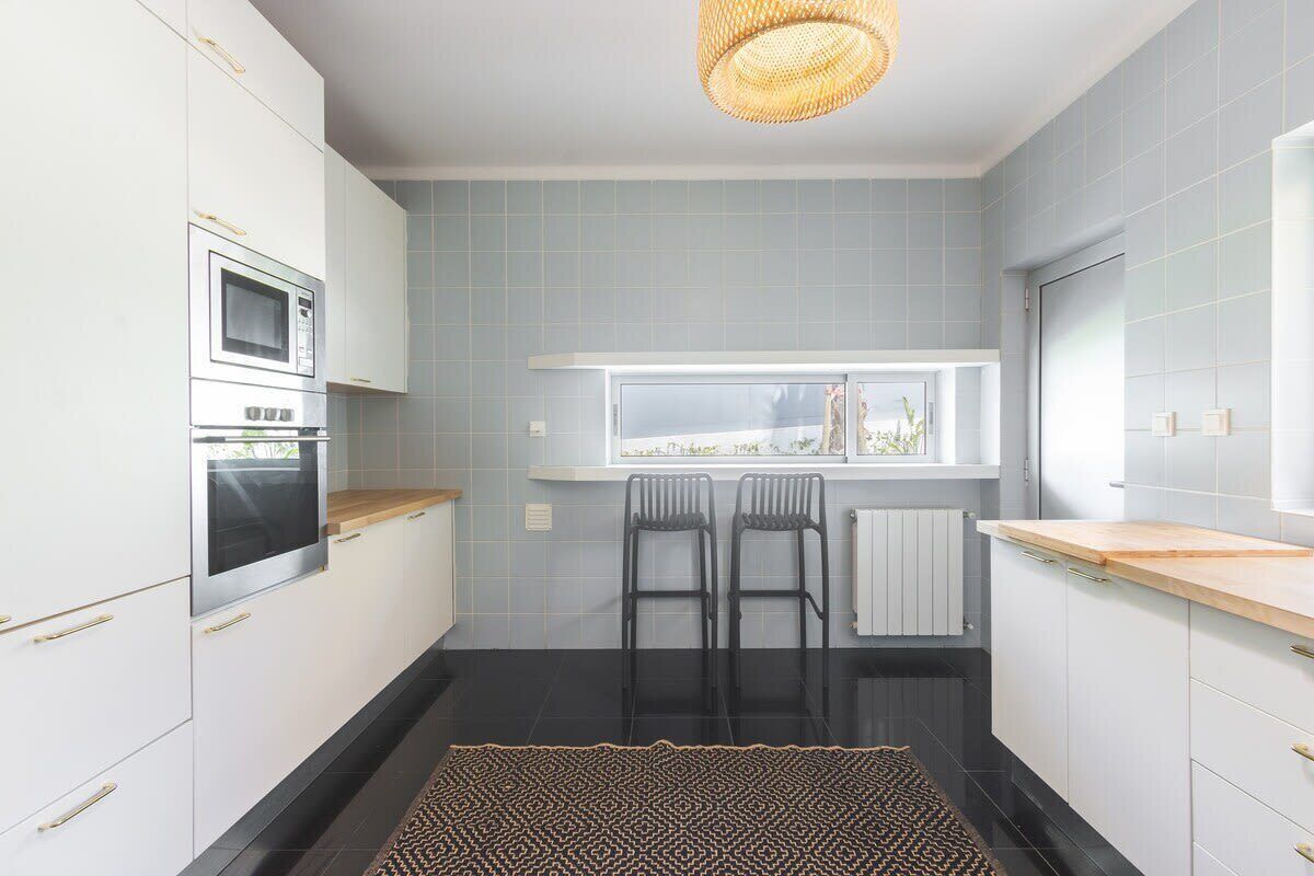 A modern kitchen with white cabinets, a microwave, a stove, and a window with a view.