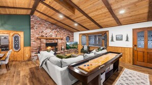 Een gezellige woonkamer met een open haard van baksteen, een pooltafel en een comfortabele zithoek.