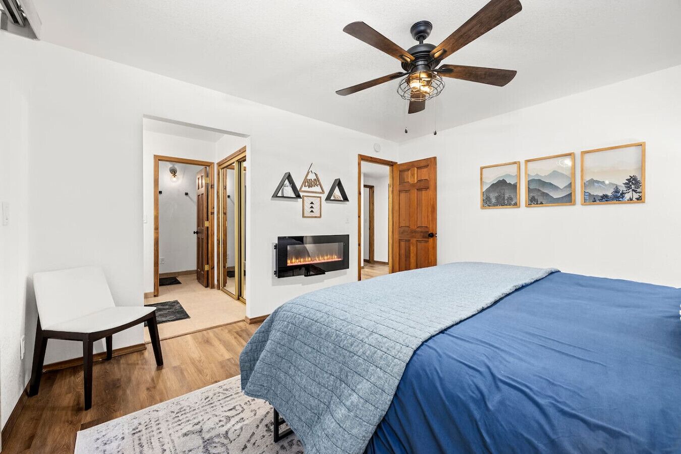 Une chambre à coucher avec un lit, une chaise, une cheminée et un ventilateur de plafond.