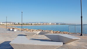An outdoor seating area with geometric concrete benches and a view of the beach and cityscape.