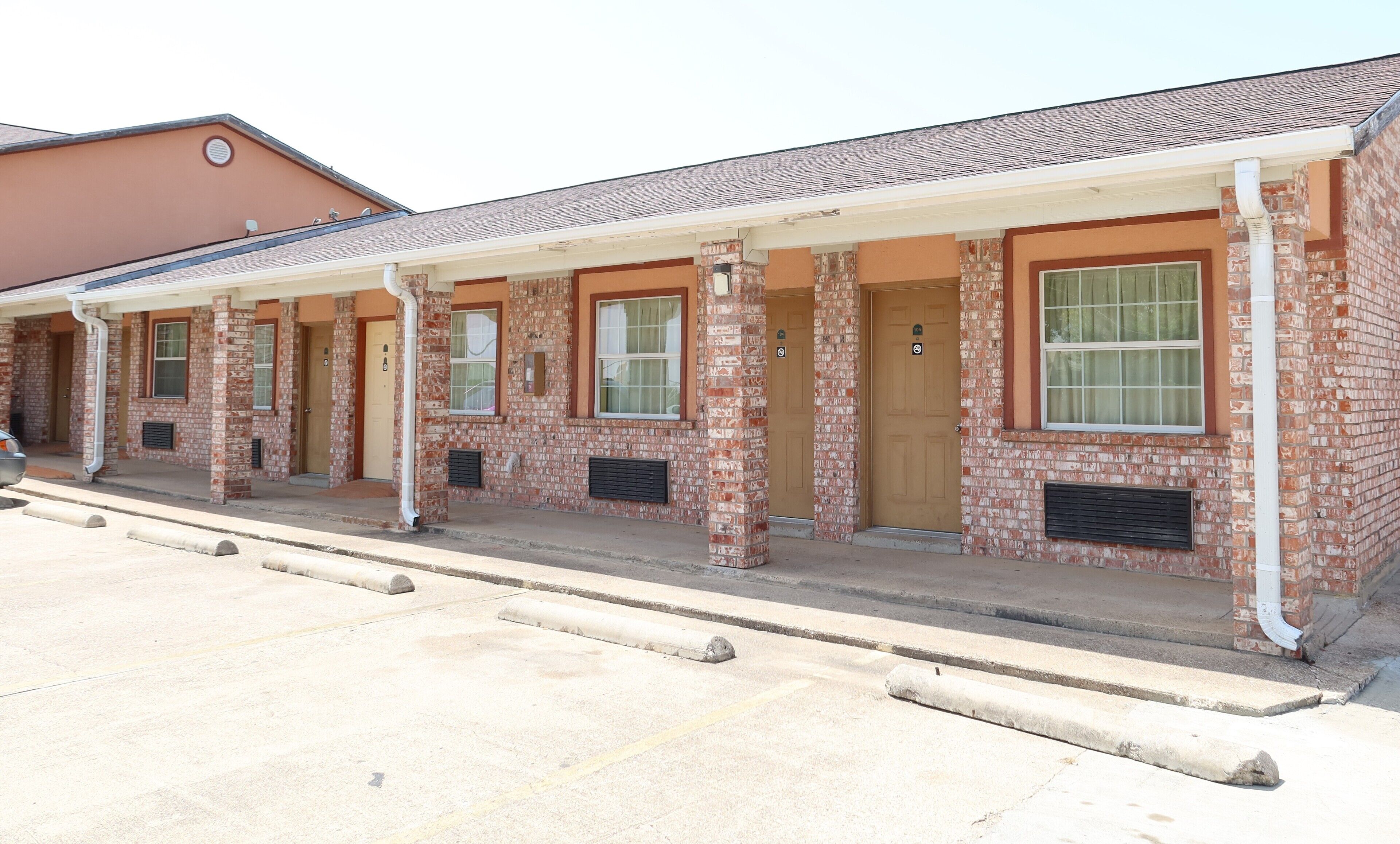 A row of brick buildings with a covered walkway, each with a door and window.