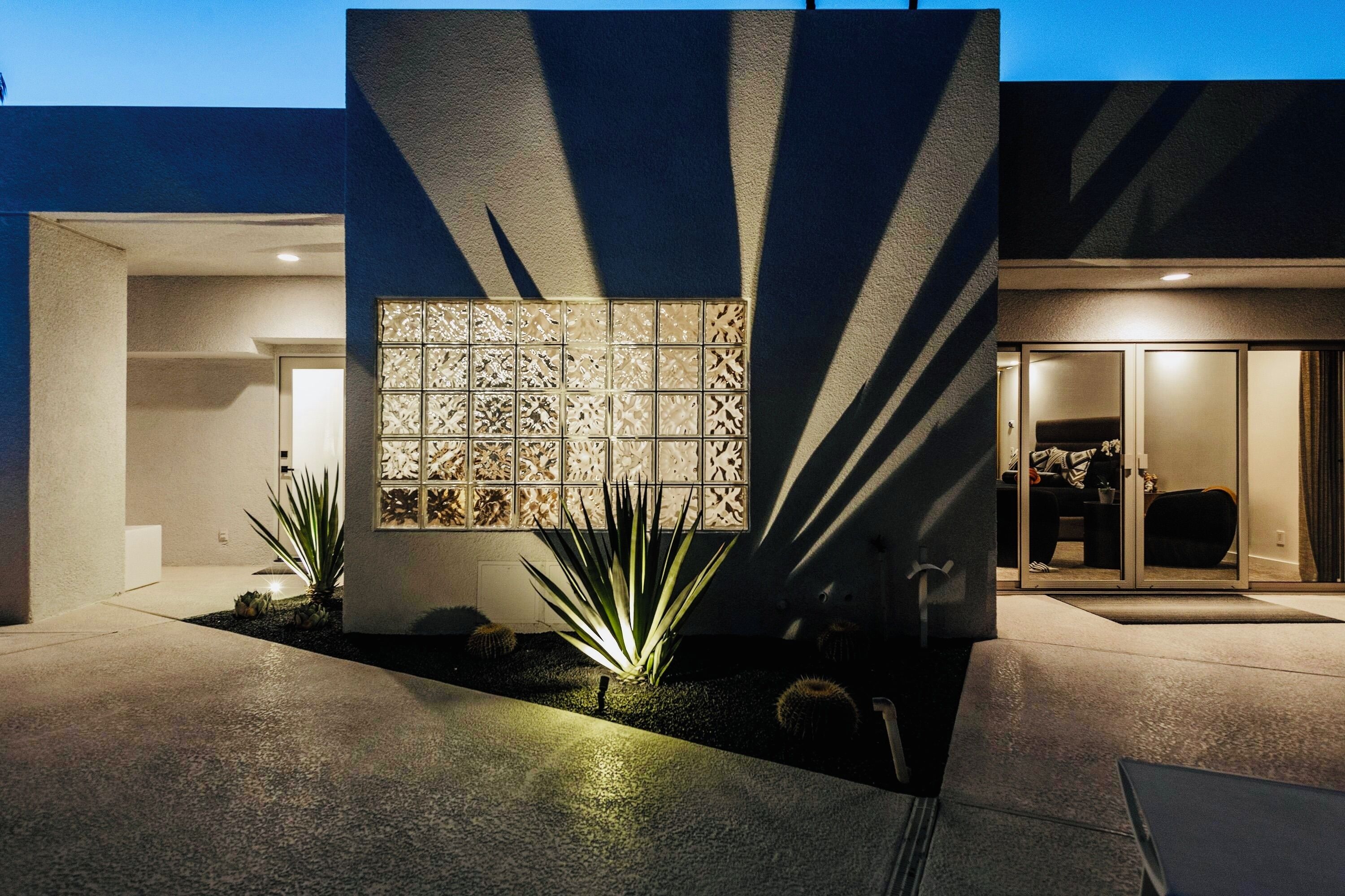 A modern building exterior with a geometric facade, a patterned wall, and a well-lit entrance.