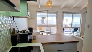Una cocina moderna con una isla central, una zona de comedor con mesa y sillas, y un balcón con vistas.