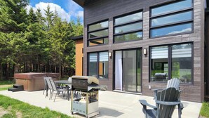 A modern house with a patio area featuring outdoor furniture, a hot tub, and a grill. - Ô paradis Spa&Massage (Weedon)