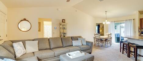 A spacious living room with a sectional sofa, ottoman, and a dining area with chairs and a table.
