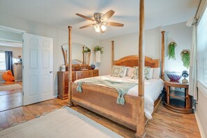 A four-poster bed with a ceiling fan, a wooden nightstand, and a small table with a lamp. - Steps to Saltwater & Sand: Townhome in Myrtle (Myrtle Beach)