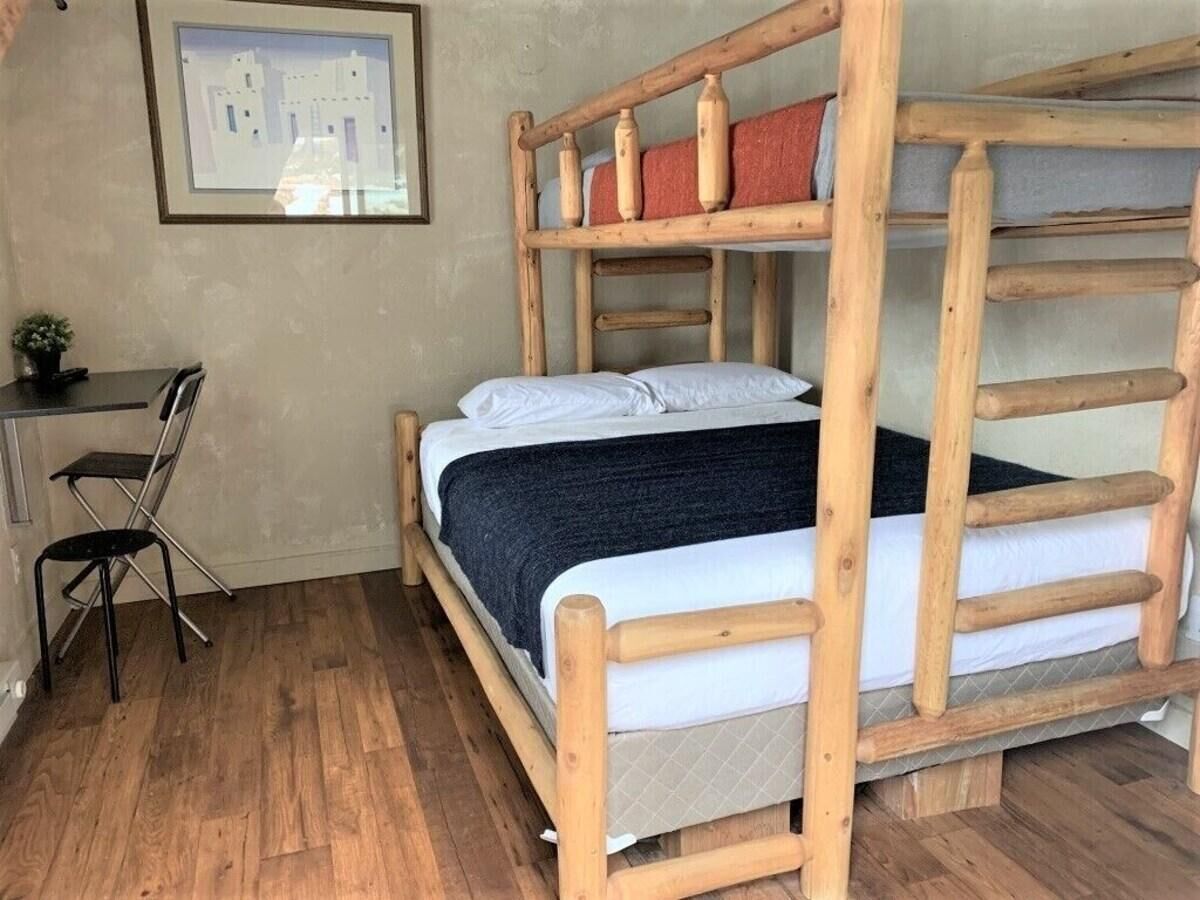 A bunk bed with a wooden frame and a desk with a chair beside it.