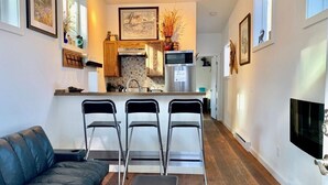 Une cuisine moderne dotée d’un îlot central, de tabourets de bar et d’un téléviseur à écran plat fixé au mur.