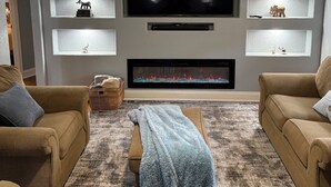 A living room with a flat-screen TV, ceiling fan, and built-in shelves with decorative items.