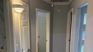 A hallway with wooden flooring, white doors, and a ceiling with a vent.