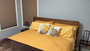 A neatly made bed with a brown headboard, a brown throw blanket, and two decorative pillows.