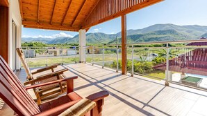A wooden deck with a view of mountains and a road.