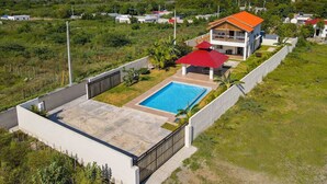 A modern house with a swimming pool, surrounded by greenery and a view of the sea. - Villa Mercedes · Pool + Mountain Views | Ocoa Bay (Hatillo)