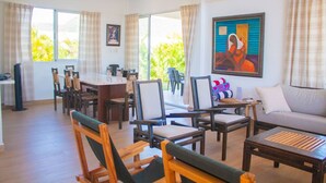 A spacious living area with a dining table, multiple chairs, a sofa, and a television.