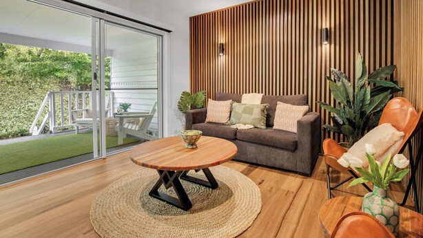 A modern living room with a sofa, coffee table, and a chair with a vase of flowers. - Bright on the River Mystic Apartment 2 (Bright)