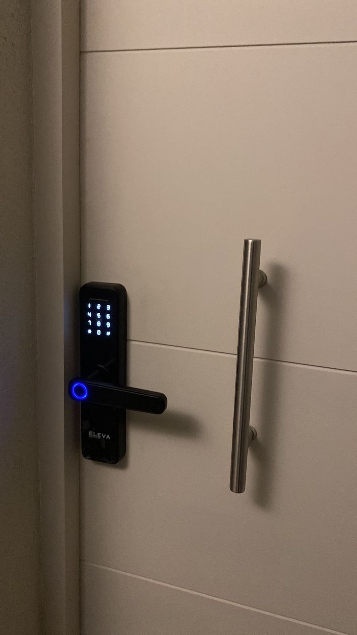 Een deur met een digitaal code slot en een metalen handgreep.