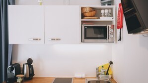 A compact kitchenette with a microwave, coffee maker, and a small sink. - Apartments Haus Altenberger - Studio, Lake view & Balcony (Zell am See)