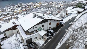 A snow-covered building with a sign reading "Haus Altenberger" and a parking area with cars. - Apartments Haus Altenberger - Studio, Lake view & Balcony (Zell am See)