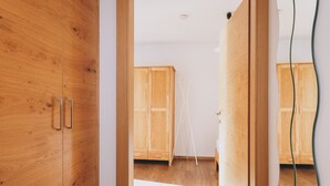 A wooden wardrobe with two handles, a white wall, and a wooden floor. - Apartments Haus Altenberger - Bergblick, Mountain view & Balcony (Zell am See)