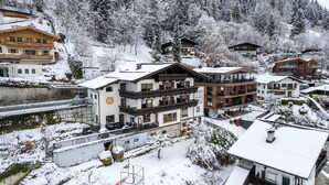 A snow-covered resort with multi-story buildings, a ski lift, and a lake. - Apartments Haus Altenberger - Bergblick, Mountain view & Balcony (Zell am See)