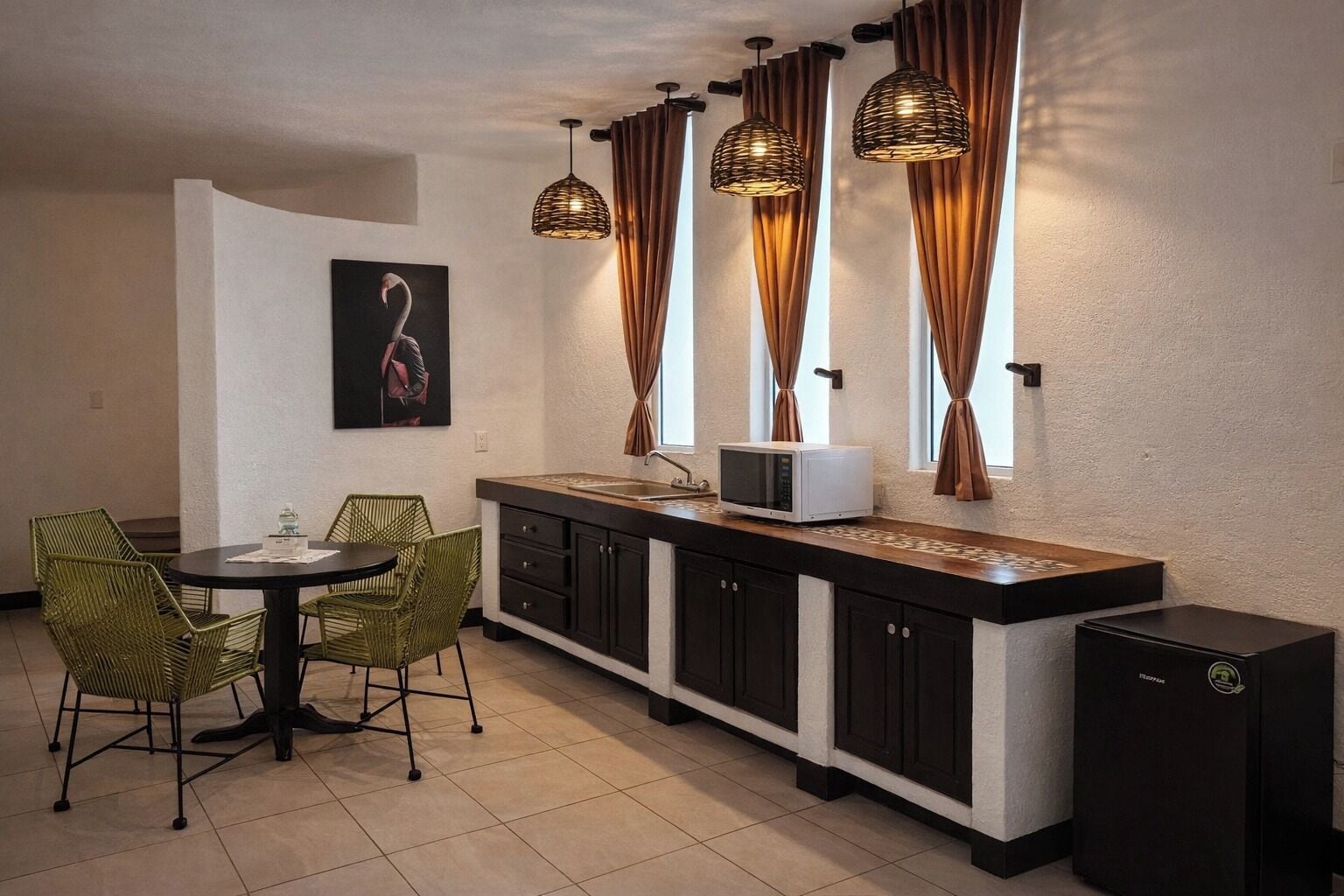 Una cocina compacta con comedor, que incluye un microondas, armarios y un refrigerador pequeño.